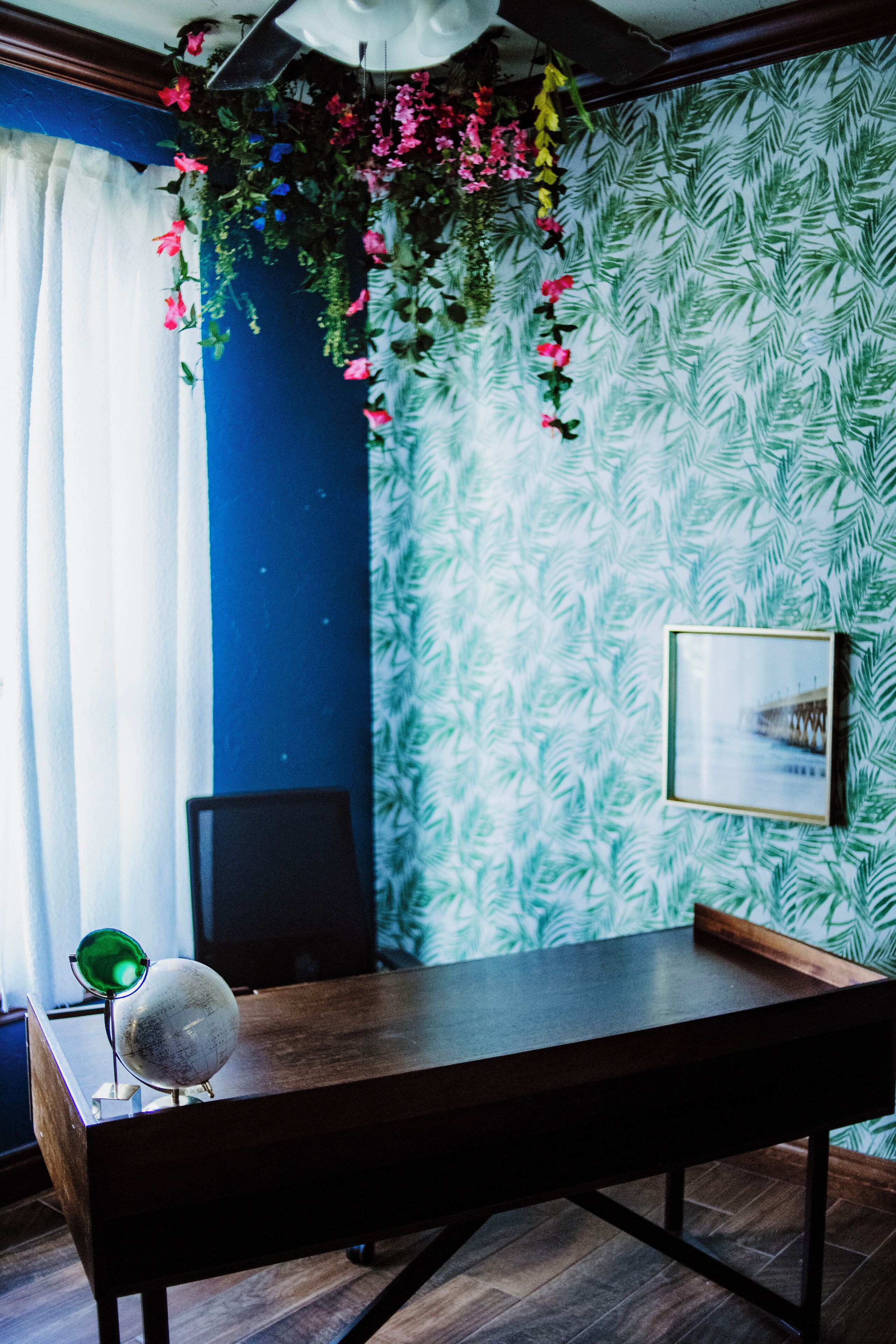 Ein Zimmer mit einem Holztisch, einem Globus und einem gerahmten Bild an der Wand.