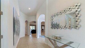 A hallway with a glass table, a wall-mounted mirror, and a painting.