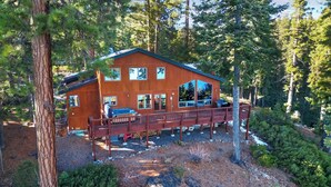 Une cabane en bois dotée d’une terrasse, entourée d’arbres.