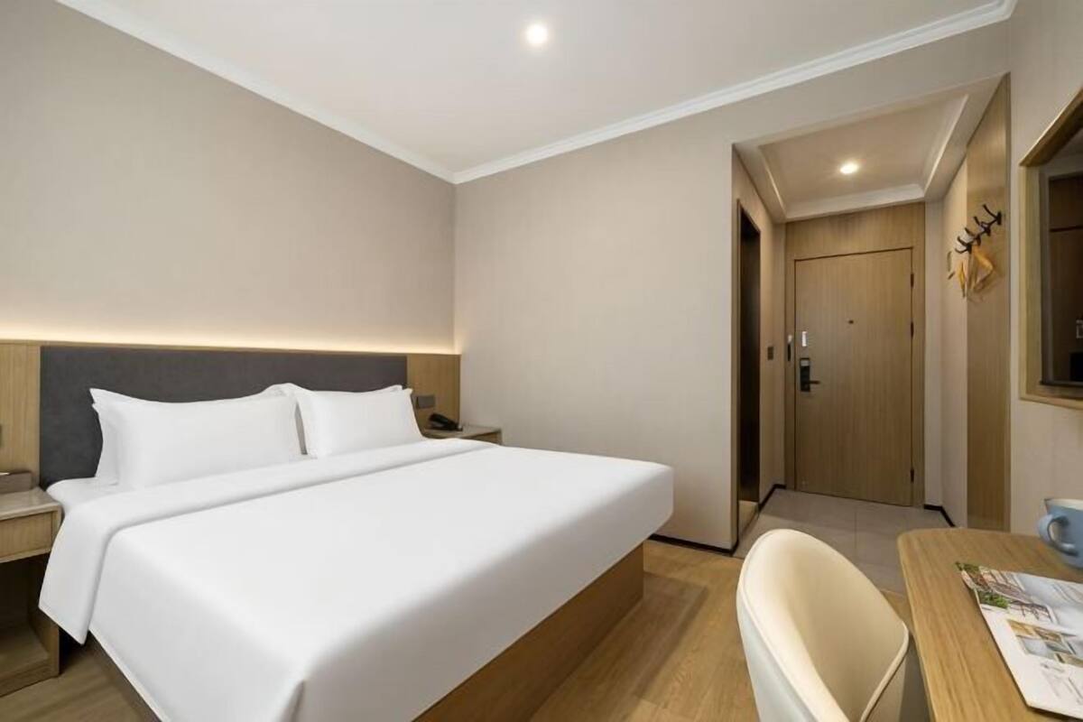 A hotel room with a large bed, bedside tables, a desk, and a chair.