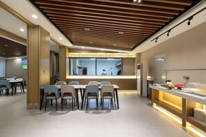 A modern dining area with a long table and chairs, a wooden ceiling, and a kitchen area visible through a glass partition. - GreenTree Inn (Affiliated Hospital of University of Traditional Chinese Medicine) (Taiyuan)