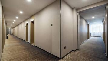A long, narrow hotel corridor with carpeted floors and doors on both sides.