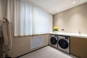 Een wasserette met een wasmachine, droger en een droogrek.