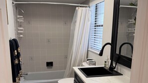Moderni kylpyhuone, jossa on kylpyamme, wc ja pesuallas.