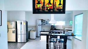 A modern kitchen with stainless steel appliances, a central island with bar stools, and a large window providing natural light. - Whole house: villa in Llano Del Pozo, Colombia (Llano Del Pozo)