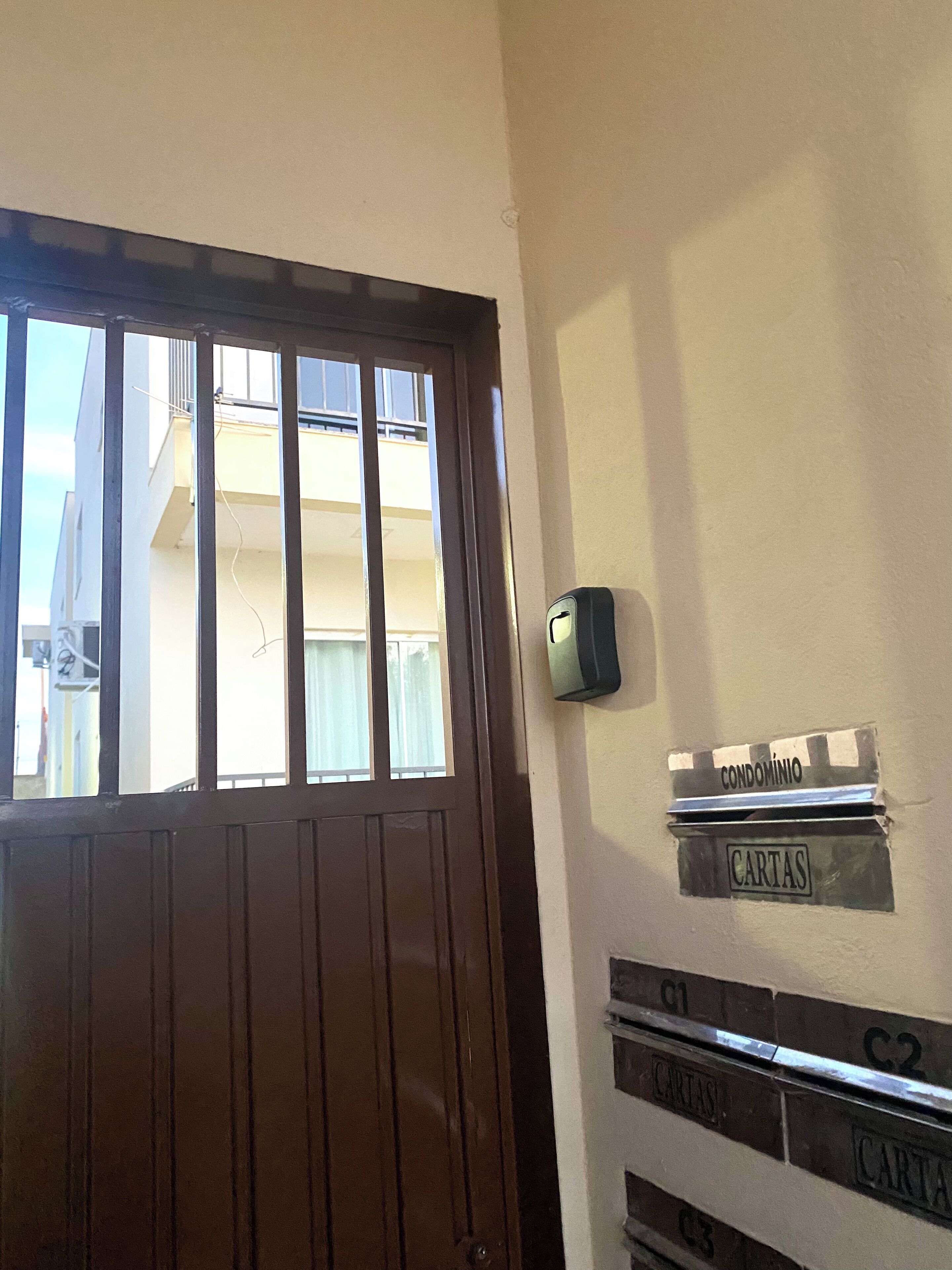 Una puerta con ventana, un buzón instalado en la pared, y un cartel que indica secciones de 'CONDOMINIO' y 'CARTAS'.