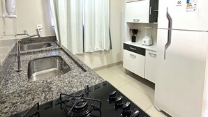 A kitchen with a gas stove, two sinks, a refrigerator, and a microwave.