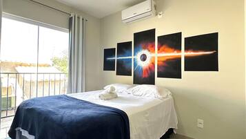 Ett hotellrum med en säng, en balkong och fyra konstverk som hänger på väggen.