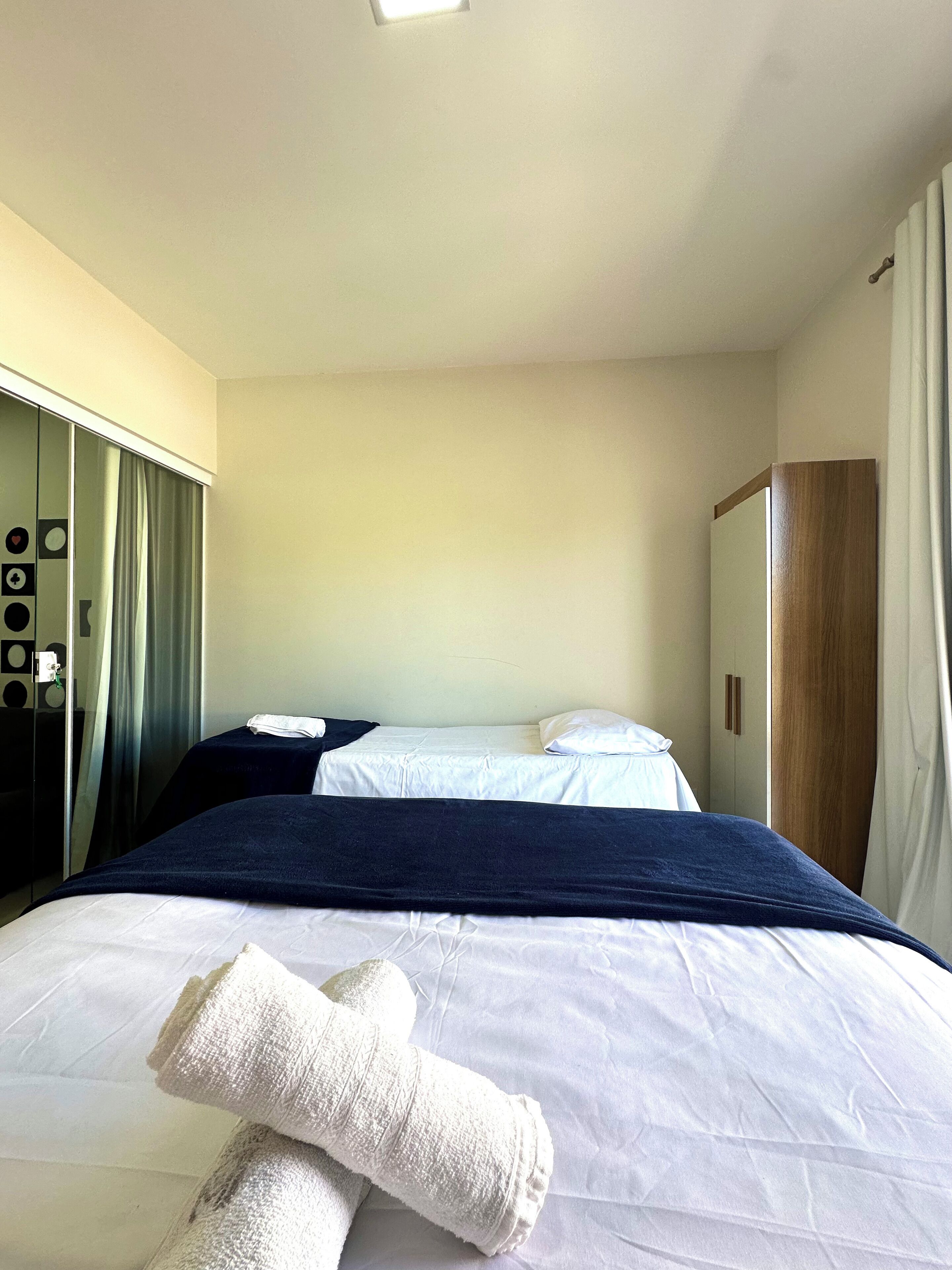 A hotel room with a bed, a wardrobe, and a mirror.