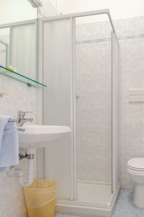 Un baño con cabina de ducha de vidrio, un lavamanos y un inodoro.