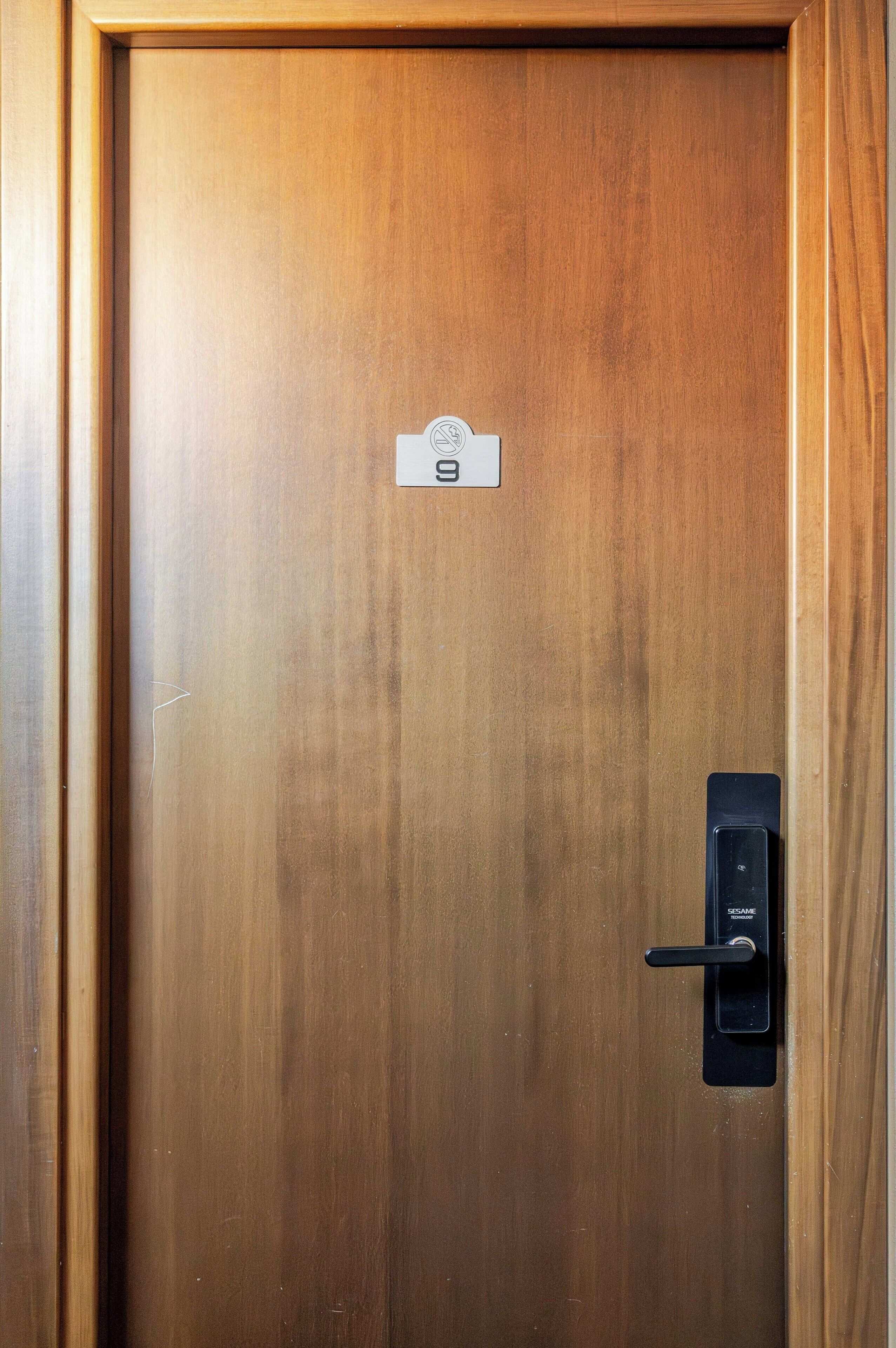 Una puerta de madera con lector de llave electrónica y un cartel que indica el número de habitación 9.