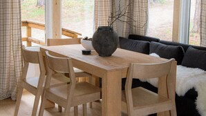A wooden dining table with chairs, a vase, and a sofa with a fur throw. - Mysa Cabin located in a beautiful wooded area outside of Deadwood - 3BR/2B (Lead)