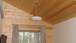 A cozy cabin interior with a wooden ceiling, a window with curtains, a sofa, and a rug. - Mysa Cabin located in a beautiful wooded area outside of Deadwood - 3BR/2B (Lead)