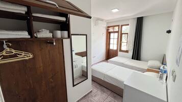 Quarto de hotel com guarda-roupa de madeira, espelho, cama, mesa de cabeceira e janela com cortinas.