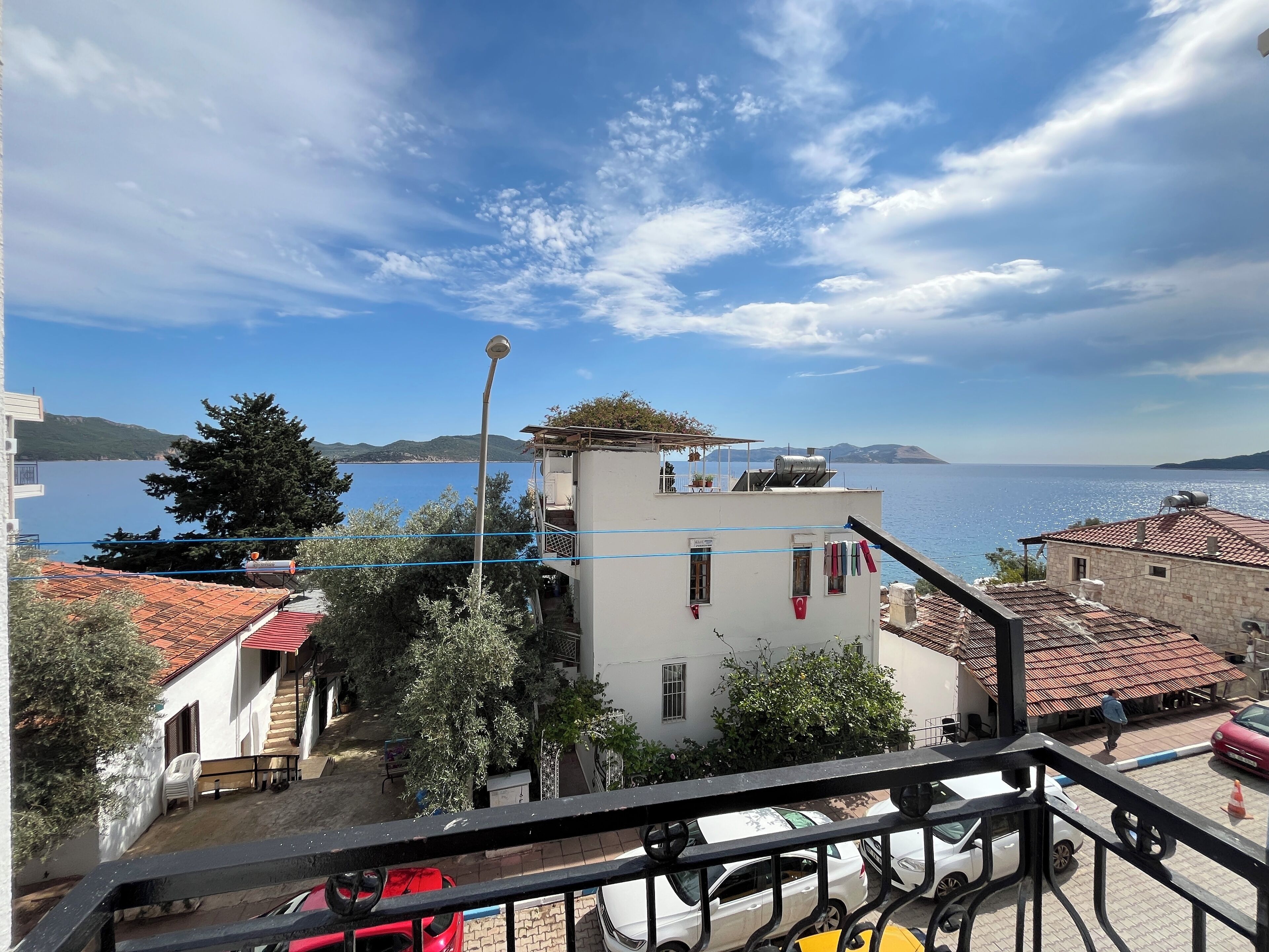 Zona residencial costera con vista al mar, edificios de techo rojo y barandilla de balcón.