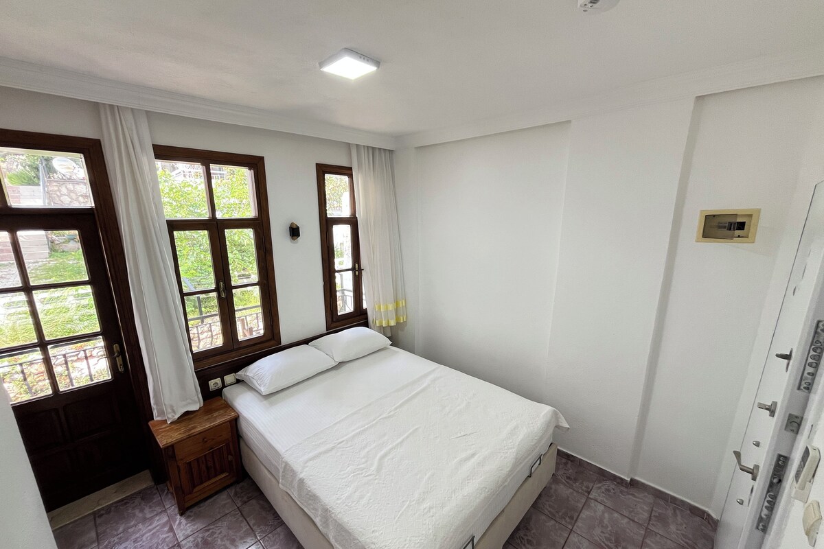 Una camera da letto con un letto, un comodino, una finestra con tende e una porta.