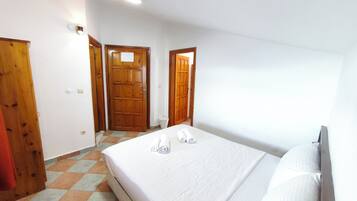 A bedroom with a bed, a wooden door, and a tiled floor.