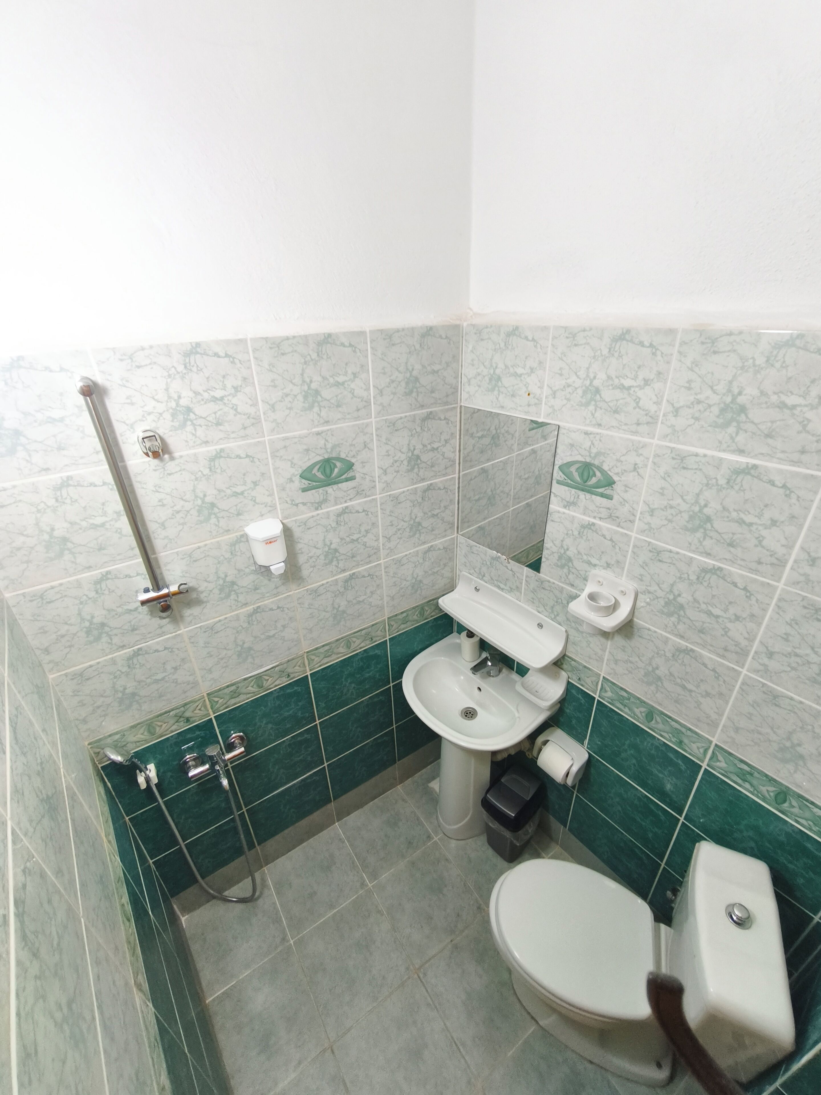 A bathroom with a toilet, bidet, sink, and handrail.