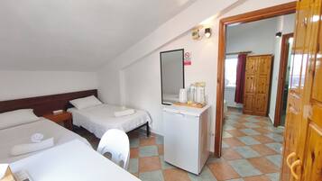 Ett hotellrum med två sängar, ett skrivbord, ett kylskåp och en spegel.
