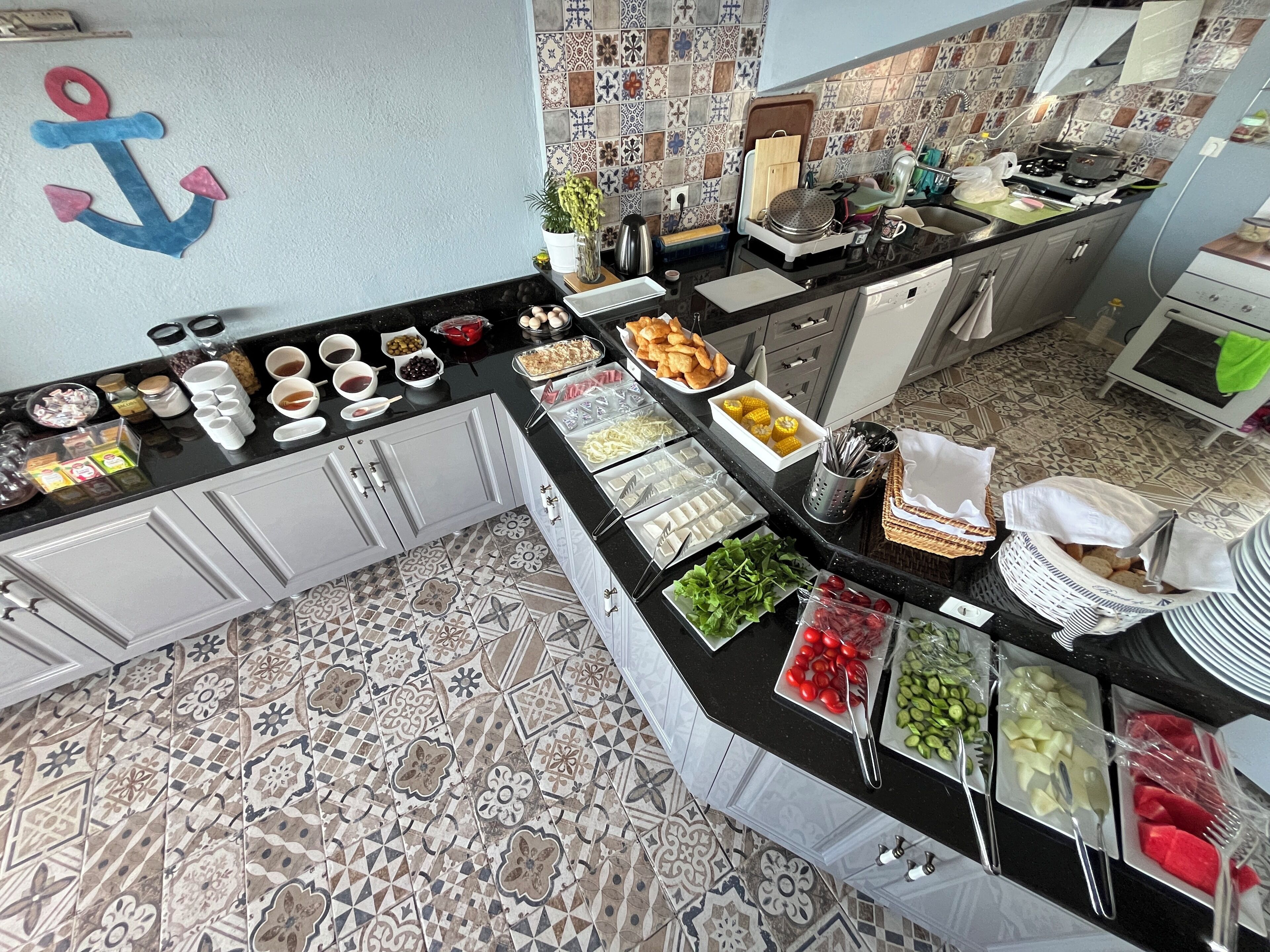 Une cuisine avec un mur recouvert de carreaux, une variété d’aliments disposés sur le plan de travail et une ancre décorative accrochée au mur.