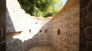 Une salle de bain aux murs en pierre, avec une petite fenêtre et un porte-serviettes.