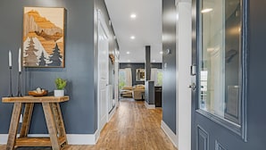 A hallway with a wooden floor, a painting on the wall, and a table with candles and a plant. - Forest Mountain Views with Yard, 3-bedroom pet friendly home Fairview (Fairview)