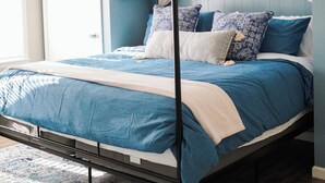 Una cama con dosel y cortinas, un ventilador de techo y un gran ventanal.