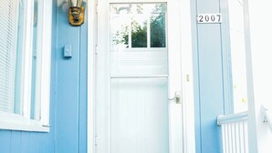 Una casa azul con una puerta blanca y el número 2007 en la puerta, además de un felpudo negro.