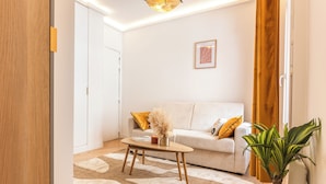 A modern living room with a sofa, a coffee table, and a potted plant. - Refined Apartment with Jacuzzi and AC - 6P PARIS 10 minutes République Bastille (Paris)