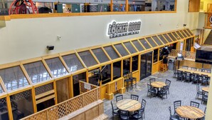 A sports bar with a wooden exterior, multiple seating areas, and a visible staircase. - Ski Paradise (Snowshoe)