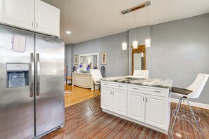 A modern kitchen with white cabinets, a stainless steel refrigerator, a marble countertop, and a bar stool. - Pet-Friendly Philly Area HQ Near Lincoln Financial (Yeadon)