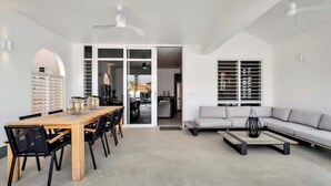 Un salon moderne avec une table à manger en bois, des chaises noires, un canapé gris et une table basse.