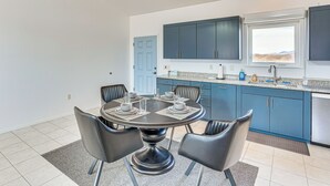 Eine moderne Küche mit dunkelblauen Schränken, einem runden Esstisch mit vier Stühlen und einem Fenster über der Spüle.