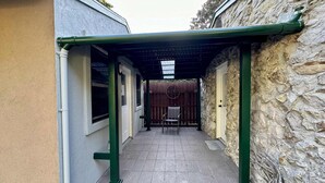 A covered outdoor area with a stone wall, a wooden fence, and a chair. - the nest (Gainesville)
