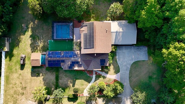 An aerial view of a residential property with a swimming pool, solar panels, and a driveway. - the nest (Gainesville)