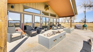 An outdoor patio with wicker furniture, a fire pit, and a large window overlooking a rural landscape. - Riverside Retreat in Bridgeport w/ Game Room! (Bridgeport)