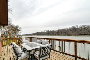 Una terraza de madera con una mesa y sillas, con vistas a un río.