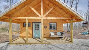 Une cabane en bois avec un toit à deux versants, une porte d’entrée, un petit porche et une balançoire.