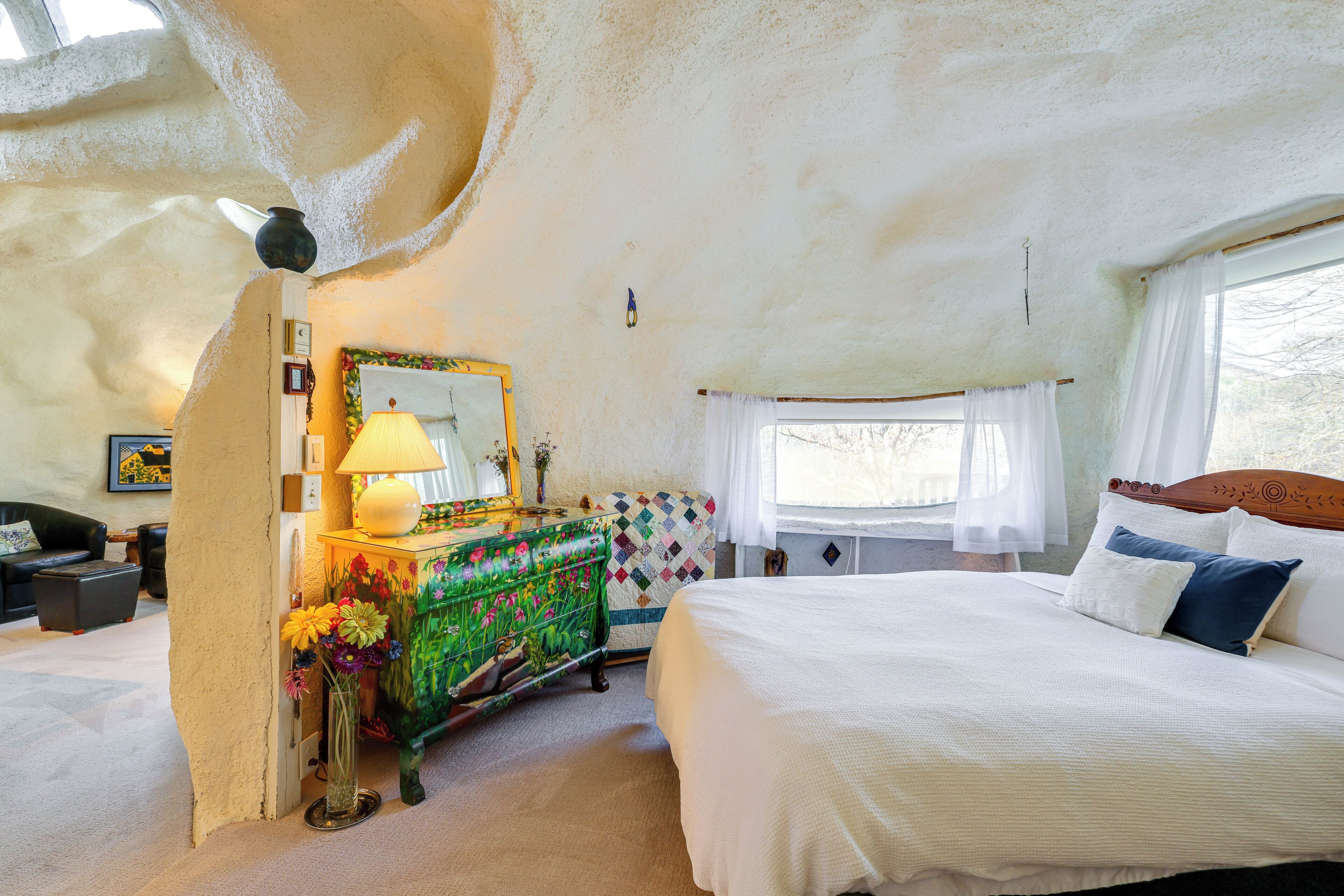Een slaapkamer met een bed, een kaptafel, een spiegel en een raam.