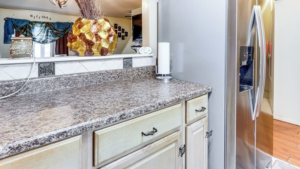 A kitchen with granite countertops, a stainless steel refrigerator, and light-colored cabinetry. - 3 Mi to Dtwn New Haven: Colorful Condo w/ Yard! (East Haven)