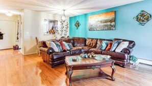 A living room with a brown leather sectional sofa, a glass coffee table, and teal walls. - 3 Mi to Dtwn New Haven: Colorful Condo w/ Yard! (East Haven)