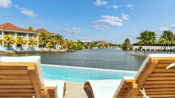 A poolside view with lounge chairs, a clear blue pool, and a waterfront view. - Waterdream Villa, Water Villas (Kralendijk)