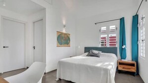A bedroom with a bed, a chair, a nightstand, a window with curtains, and a wall-mounted globe. - Waterdream Villa, Water Villas (Kralendijk)
