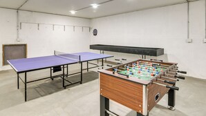 A room with a ping pong table, a foosball table, and a dartboard on the wall. - 6 Mi to Dtwn Pella: Riverfront Cabin w/ Game Room! (Pella)