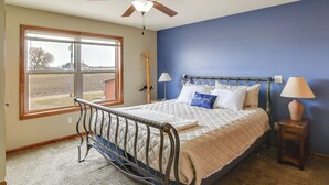 A bedroom with a bed, a window, a ceiling fan, and a nightstand with a lamp. - 6 Mi to Dtwn Pella: Riverfront Cabin w/ Game Room! (Pella)