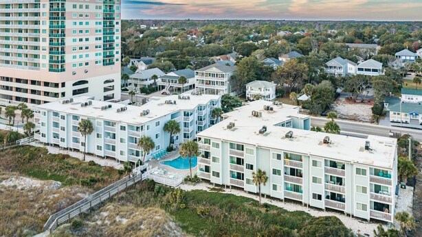 Um hotel à beira-mar com vários edifícios, uma piscina e acesso direto à praia.