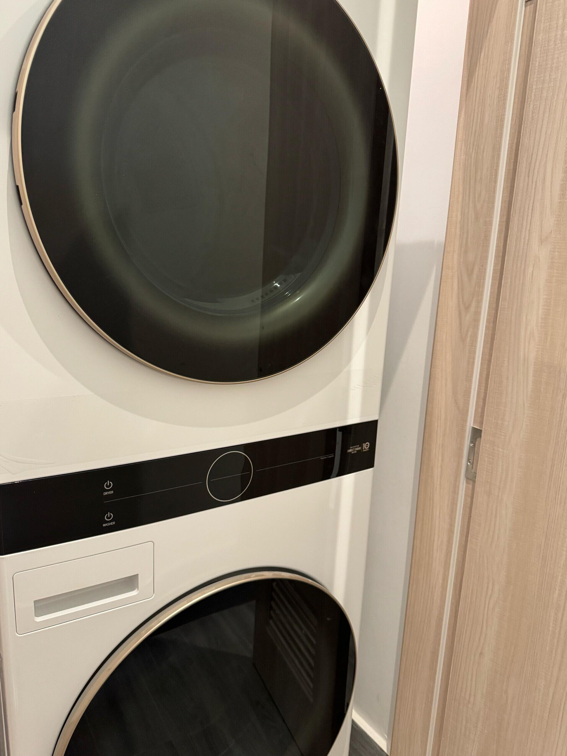 A stacked washer and dryer unit with a control panel and a wooden door.