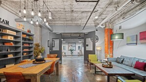 A spacious, industrial-style interior with exposed ceilings, a long wooden table, and a comfortable seating area. - Downtown Dallas Loft (Dallas)