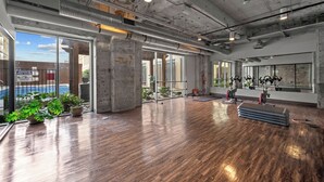 A spacious indoor area with a wooden floor, large windows, and exercise equipment. - Downtown Dallas Loft (Dallas)