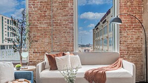 A modern living room with a large window, a sofa, a coffee table, and a floor lamp. - Downtown Dallas Loft (Dallas)